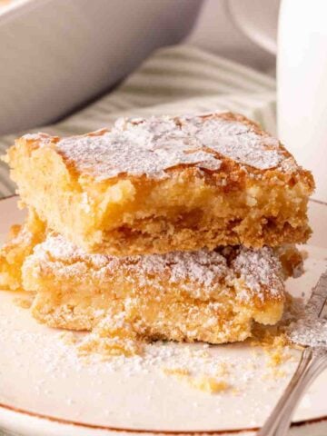 Two slices of gooey butter cake stacked on a plate with a fork.