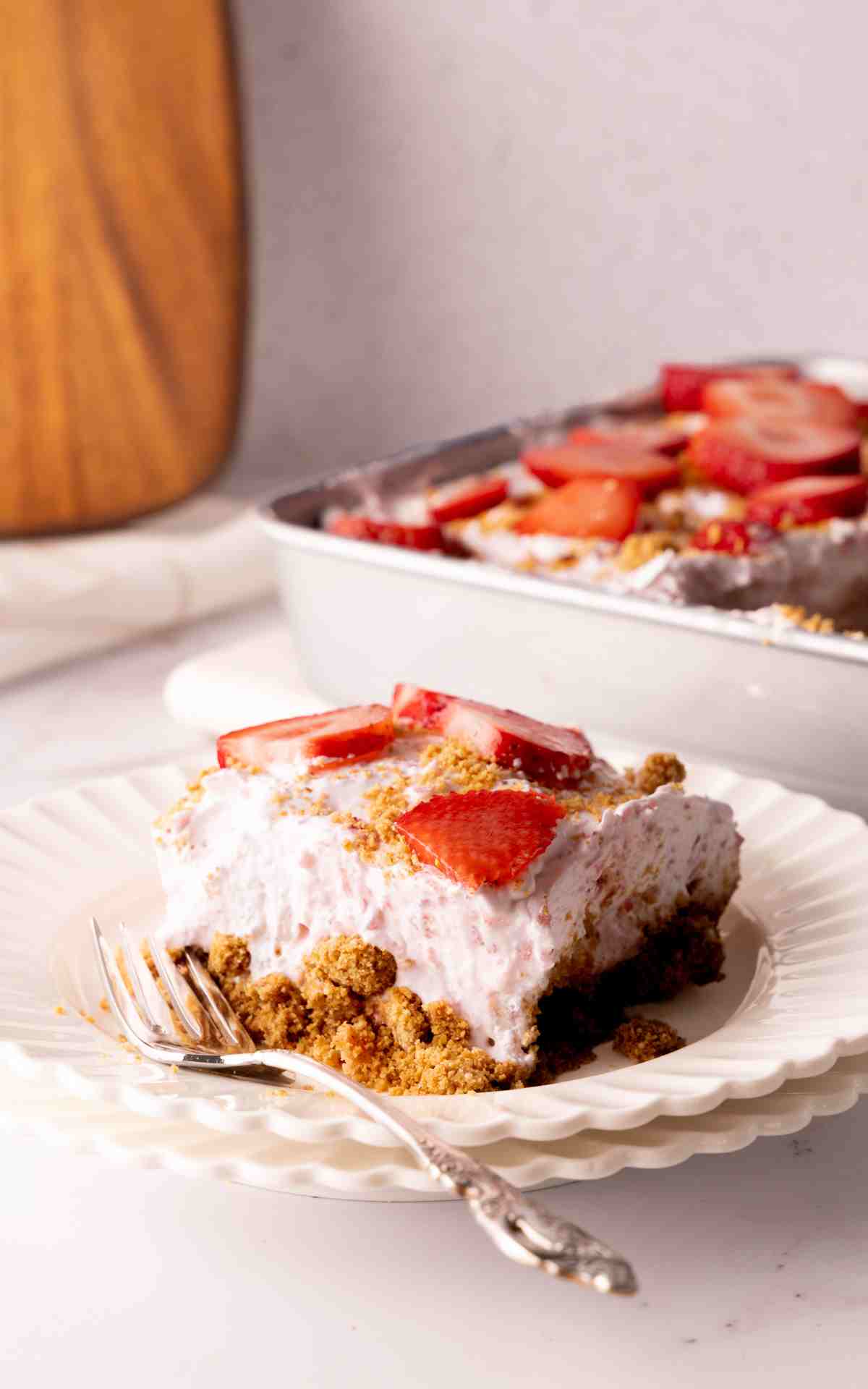 A slice of strawberry delight on a saucer with a fork.
