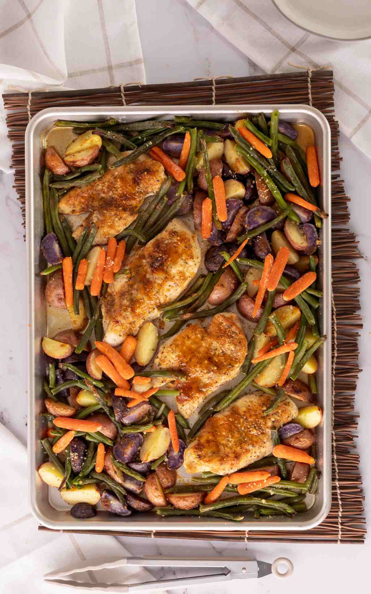Top view chicken and veggies in a sheet pan.