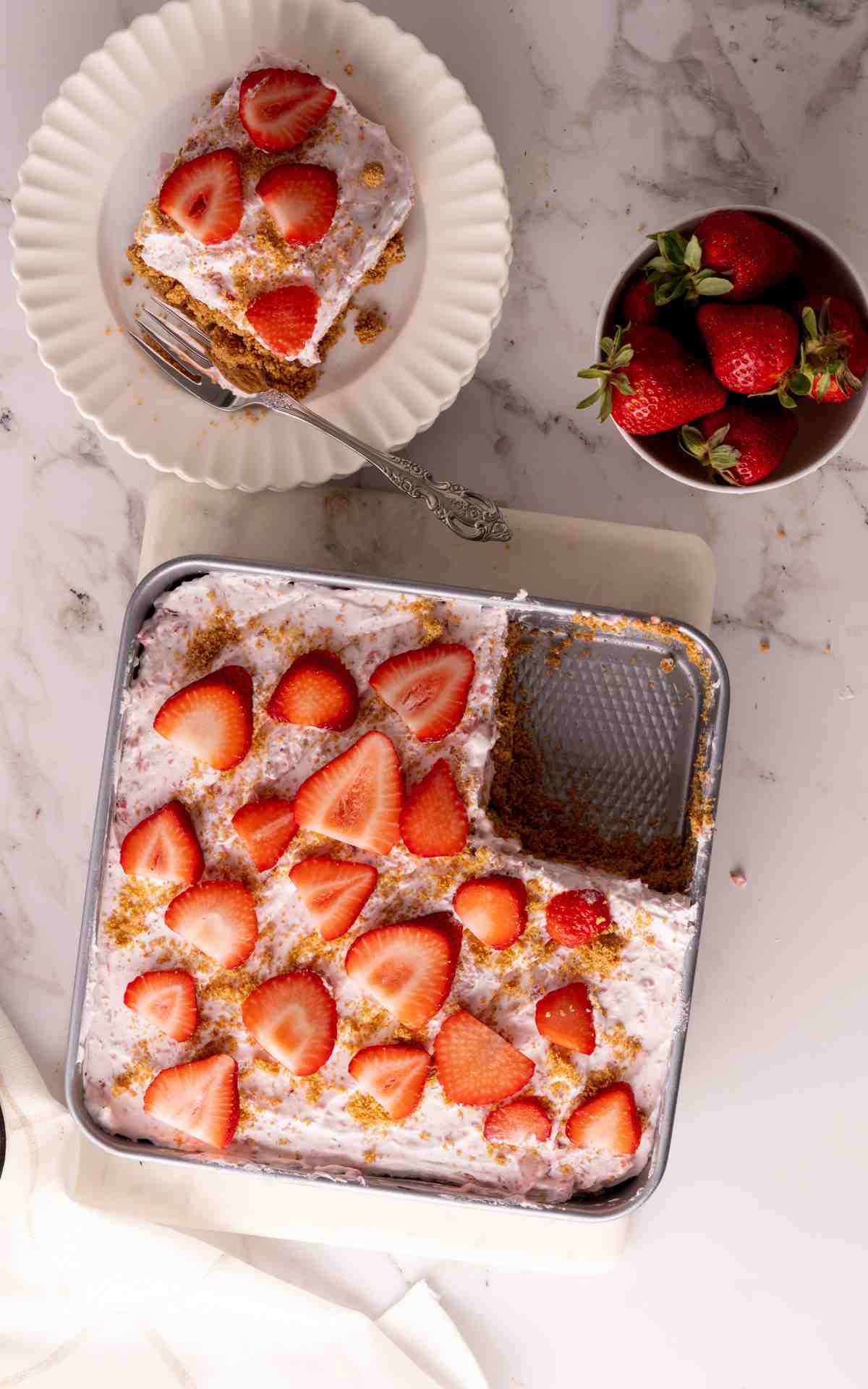 Top view of a a strawberry dessert topped with sliced strawberries and graham cracker crumbs.