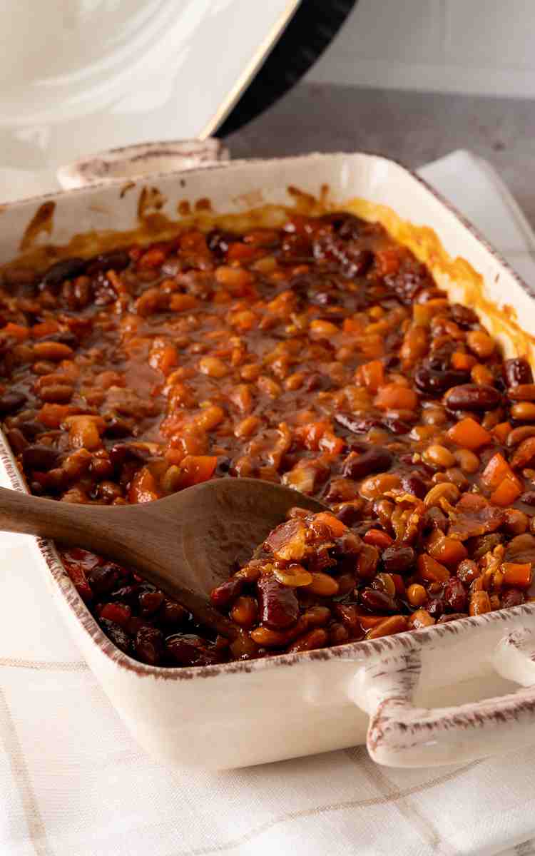 Hot barbecue beans on a linen napkin with a serving spoon.
