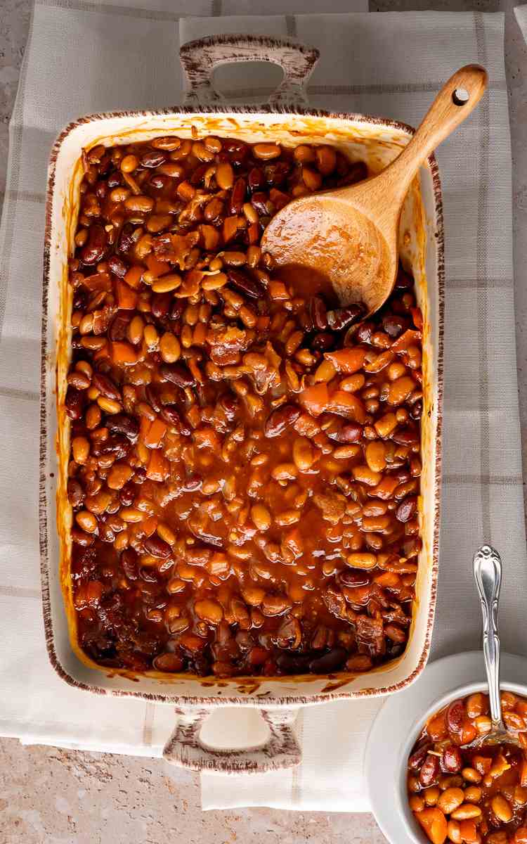 Overhead of baked beans with bacon served as a cookout side dish.