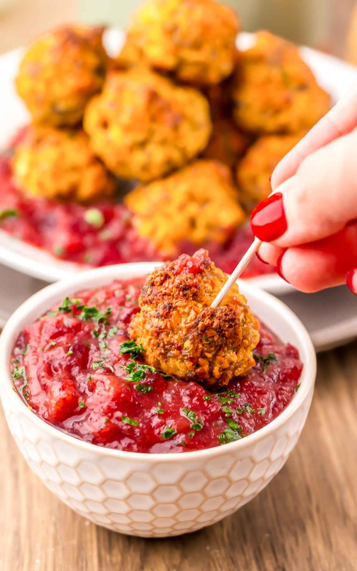 Holiday sausage balls appetizer dipped in cranberry sauce.